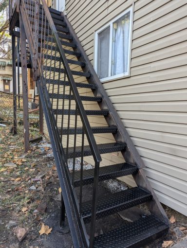 New treads and repaired handrail on commercial fire escape.